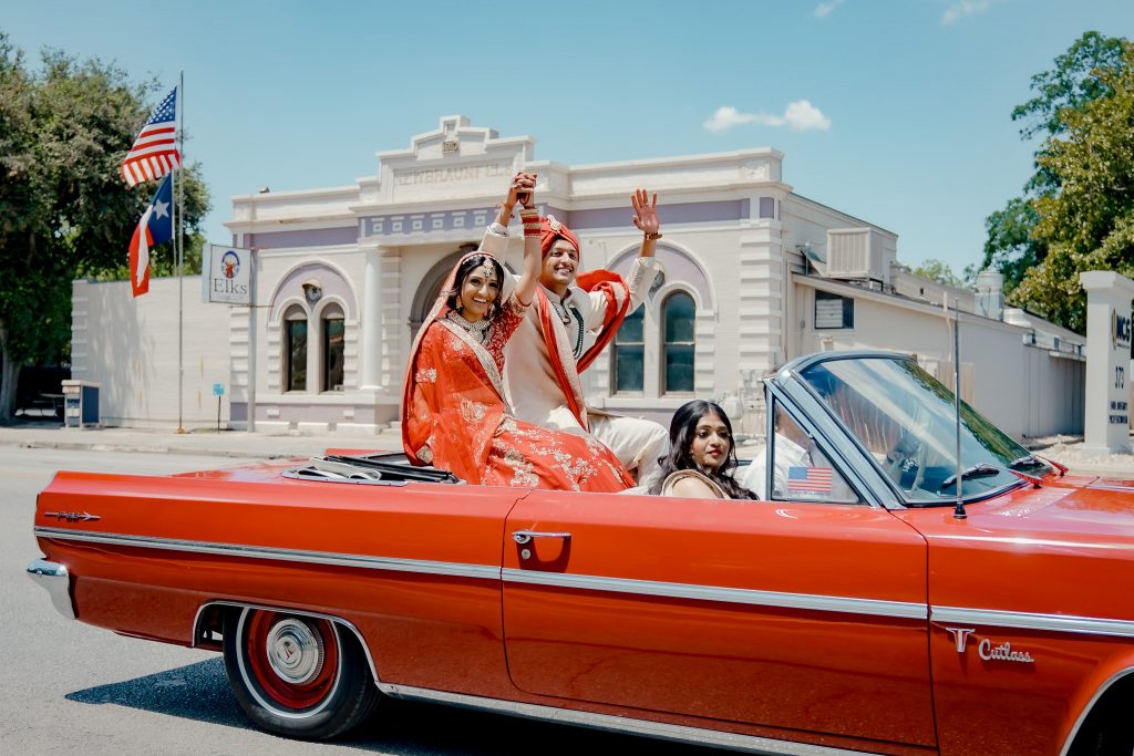 couple grand exit in a vintage red car